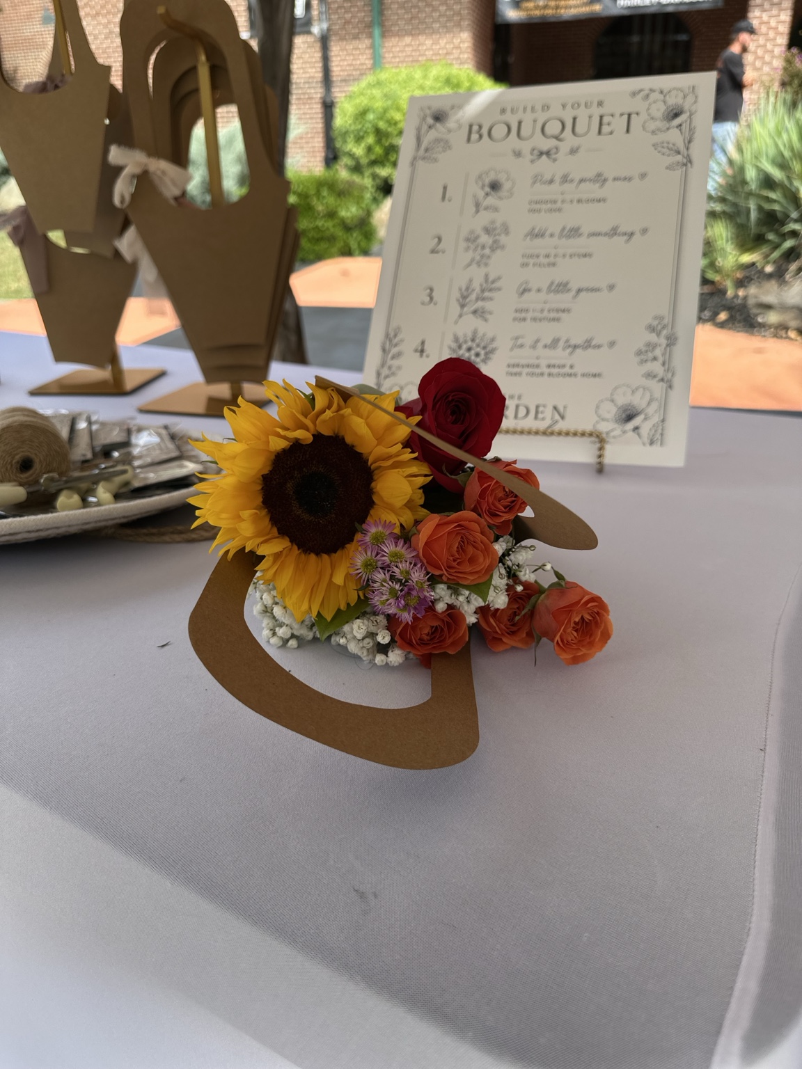 Finished sunflower bouquet beside The Garden Social NC build your bouquet sign